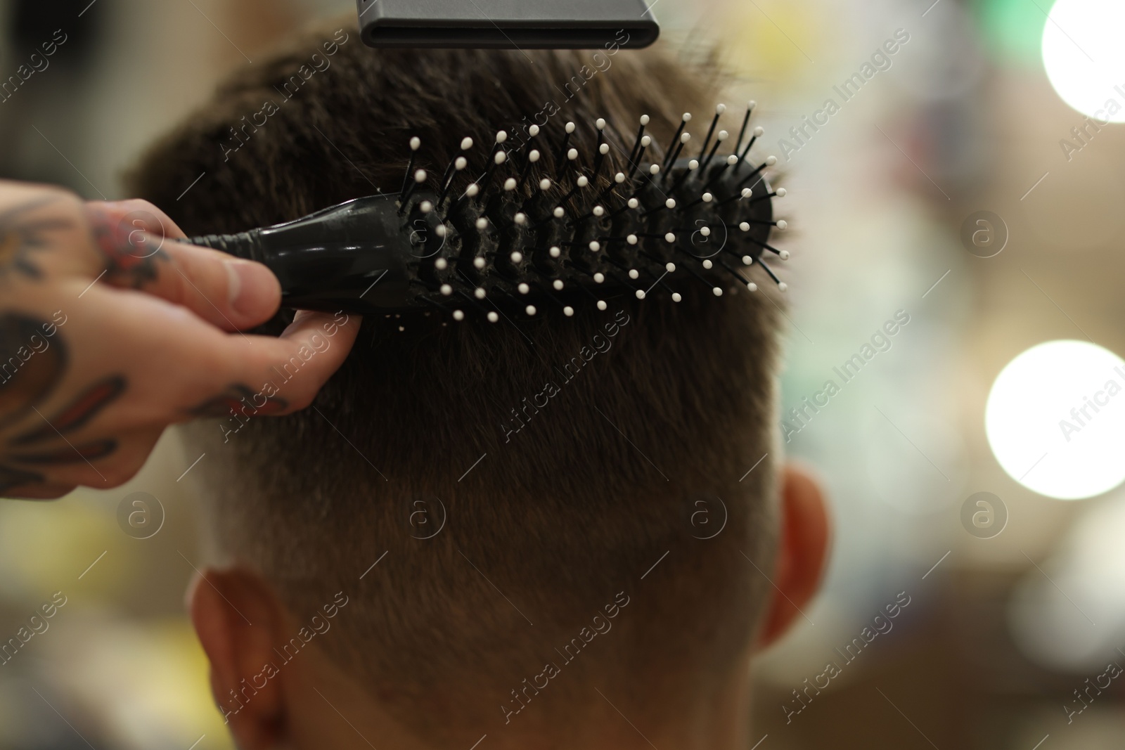 Professional barber blow drying client's hair in barbershop, closeup Photo of Professional barber blow drying client's hair in barbershop, closeup