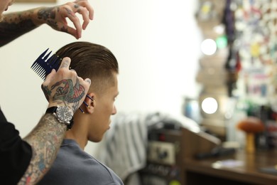 Photo of Professional barber working with client in barbershop, closeup. Space for text