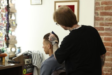 Photo of Professional barber working with client in barbershop