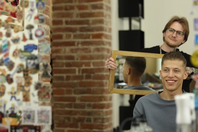 Photo of Professional barber working with client in barbershop, space for text
