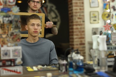 Photo of Professional barber working with client in barbershop, space for text