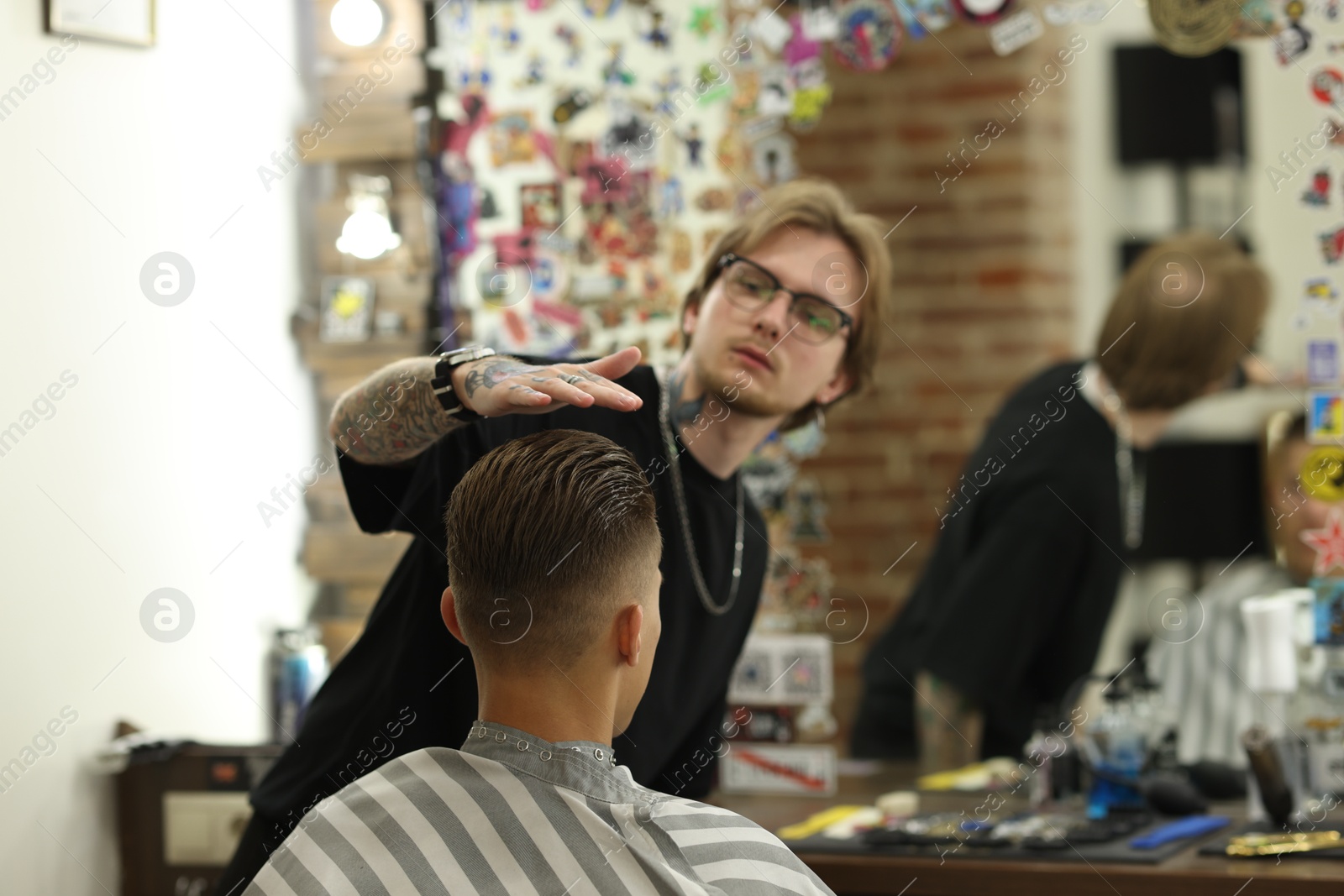 Professional barber working with client in barbershop, selective focus Photo of Professional barber working with client in barbershop, selective focus