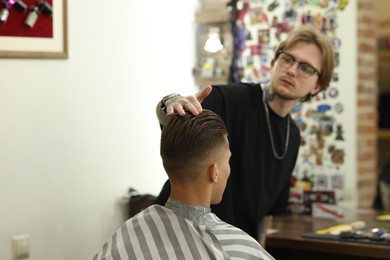 Photo of Professional barber working with client in barbershop, selective focus