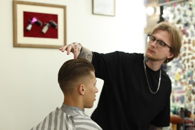 Photo of Professional barber working with client in barbershop, selective focus