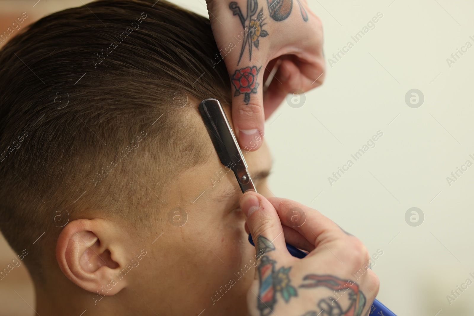 Professional barber working with client in barbershop, closeup Photo of Professional barber working with client in barbershop, closeup