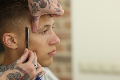 Photo of Professional barber working with client in barbershop, closeup. Space for text