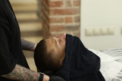 Photo of Professional barber working with client in barbershop, closeup