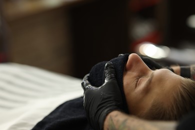 Photo of Professional barber working with client in barbershop, closeup. Space for text