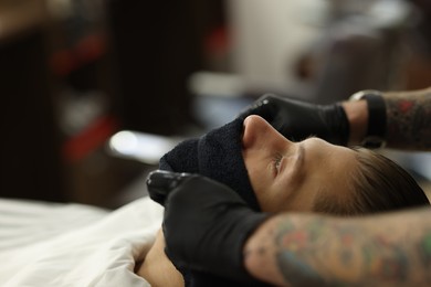 Photo of Professional barber working with client in barbershop, closeup. Space for text