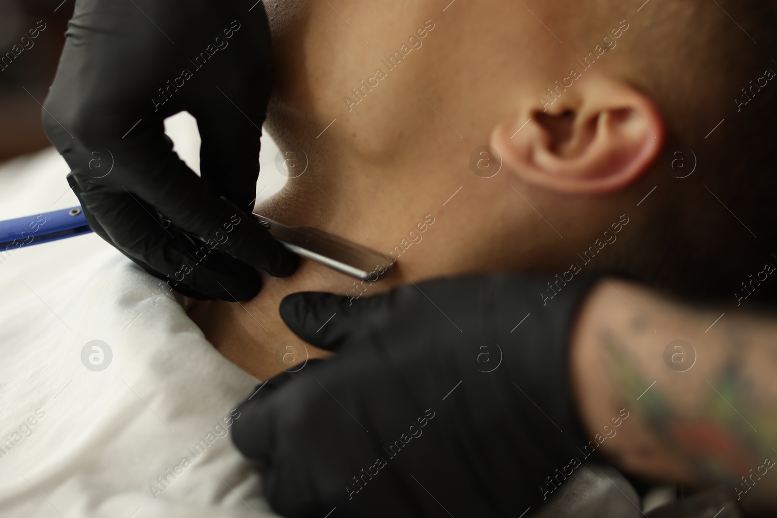 Professional barber working with client in barbershop, closeup Photo of Professional barber working with client in barbershop, closeup