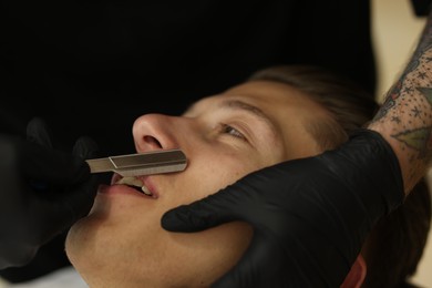 Photo of Professional barber working with client in barbershop, closeup