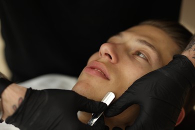 Photo of Professional barber working with client in barbershop, closeup