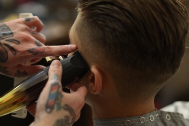 Photo of Professional barber working with client in barbershop, closeup