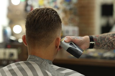 Photo of Professional barber working with client in barbershop, closeup