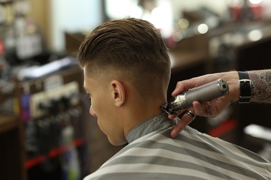 Photo of Professional barber working with client in barbershop, closeup