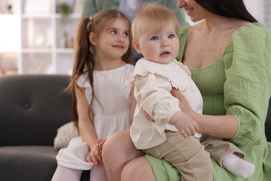 Photo of Happy parents and their kids together on sofa at home, closeup