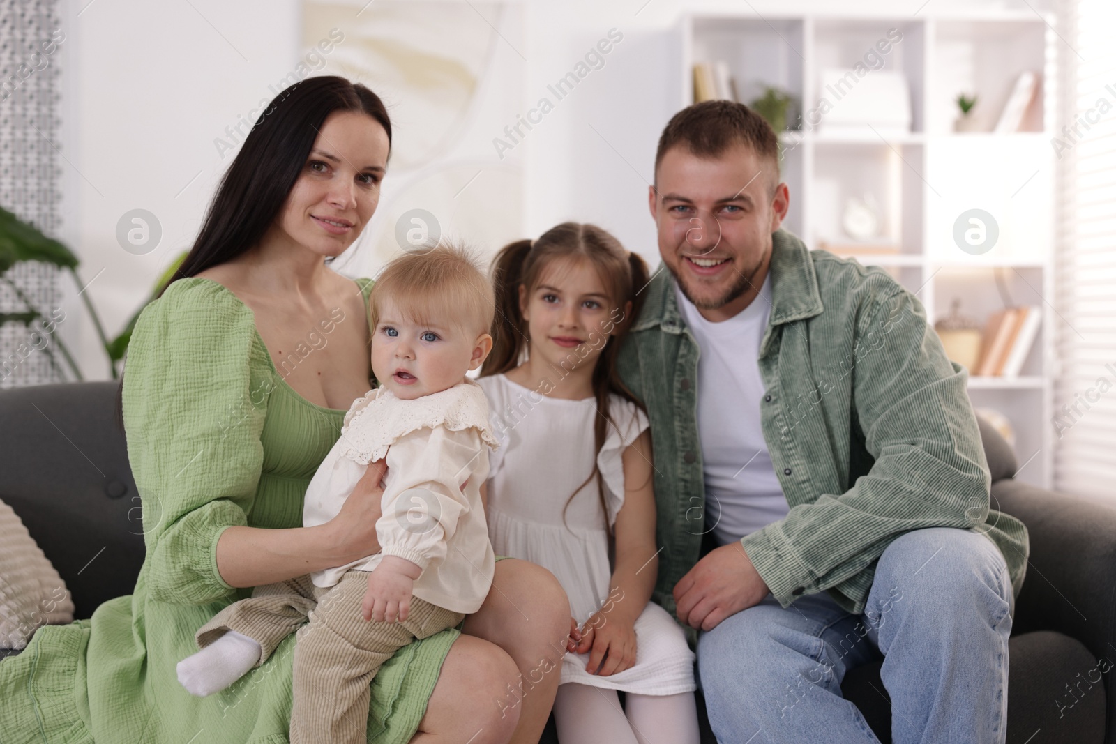 Happy parents and their kids together on sofa at home Photo of Happy parents and their kids together on sofa at home