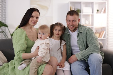 Photo of Happy parents and their kids together on sofa at home