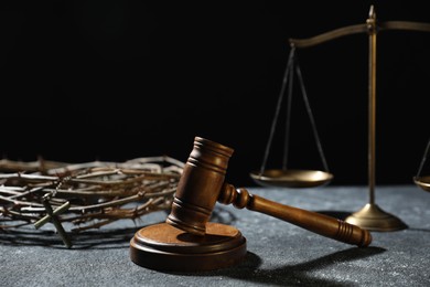 Photo of Crown of thorns, judge's gavel and scales on dark textured background. Space for text