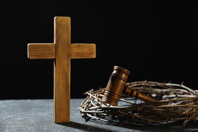 Photo of Crown of thorns, judge's gavel and wooden cross on dark textured background
