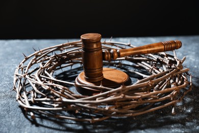 Photo of Crown of thorns and judge's gavel on dark textured background, closeup