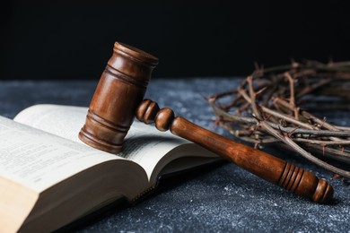 Photo of Crown of thorns, judge's gavel and Bible on dark textured background, closeup