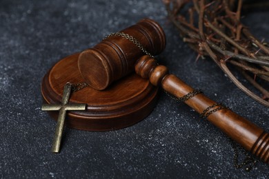 Photo of Crown of thorns and judge's gavel with cross on dark textured background, closeup