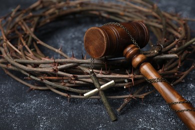 Photo of Crown of thorns and judge's gavel with cross on dark textured background, closeup