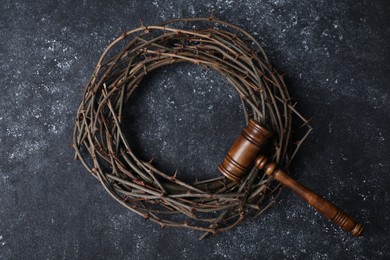 Photo of Crown of thorns and judge's gavel on dark textured background, top view