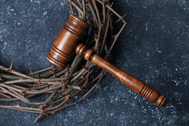 Photo of Crown of thorns and judge's gavel on dark textured background, top view