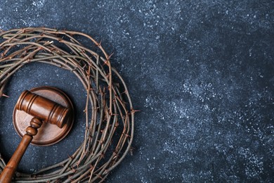 Photo of Crown of thorns and judge's gavel on dark textured background, top view. Space for text