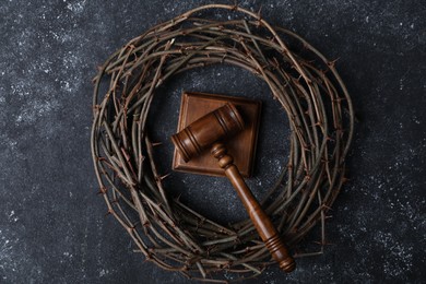 Photo of Crown of thorns and judge's gavel on dark textured background, top view