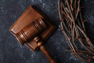 Photo of Crown of thorns and judge's gavel on dark textured background, top view