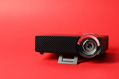 Photo of Modern video projector on red background, closeup