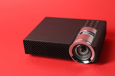 Photo of Modern video projector on red background, closeup