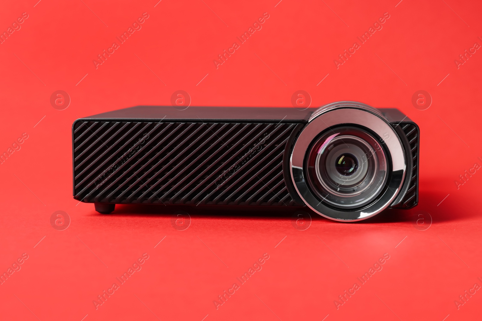 Modern video projector on red background, closeup Photo of Modern video projector on red background, closeup