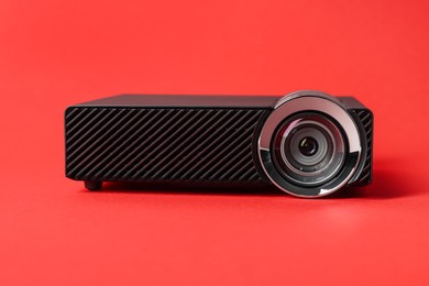 Photo of Modern video projector on red background, closeup