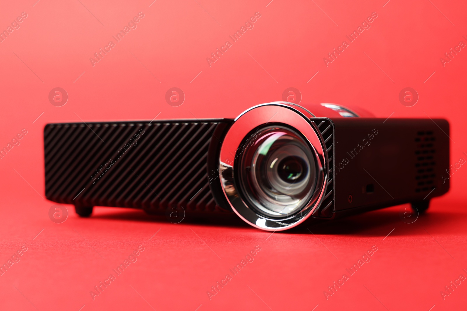 Photo of Modern video projector on red background, closeup