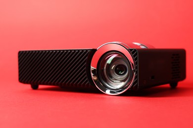 Photo of Modern video projector on red background, closeup