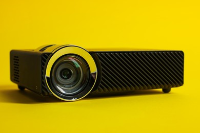 Photo of Modern video projector on yellow background, closeup