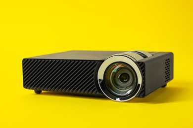 Photo of Modern video projector on yellow background, closeup