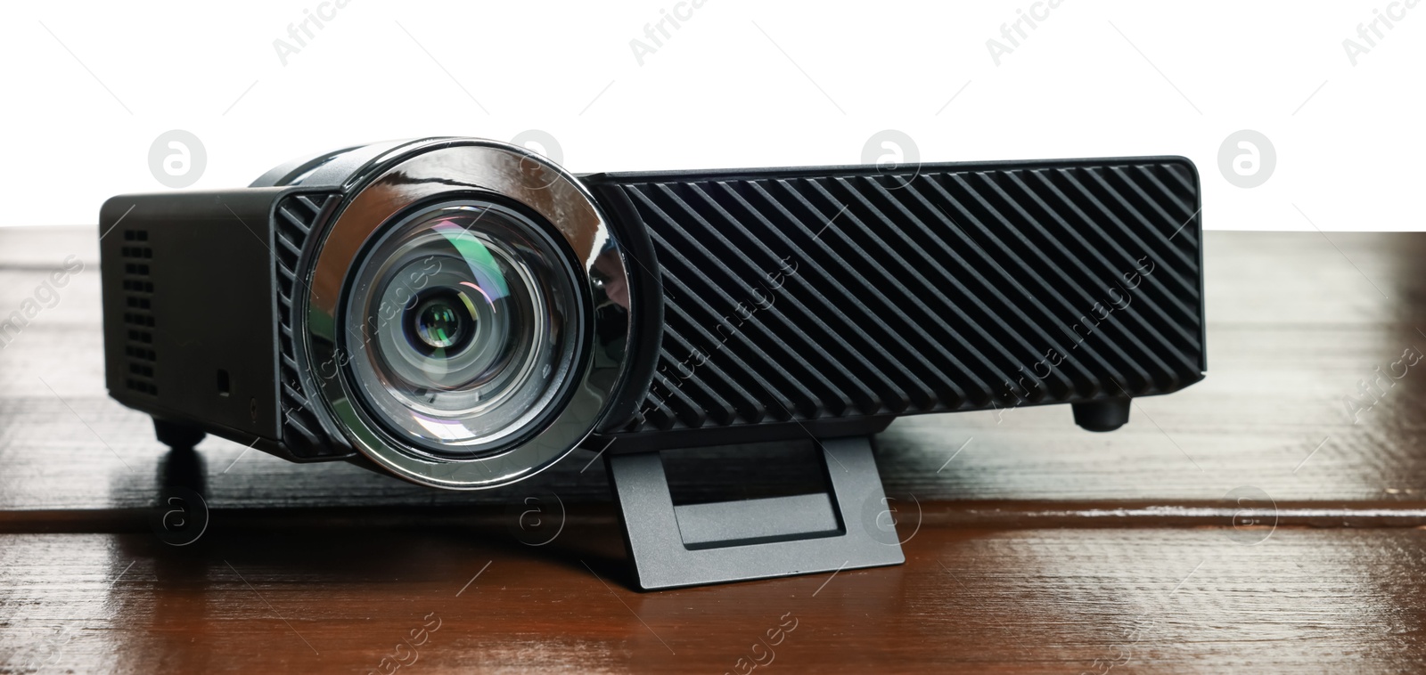 Modern video projector on wooden table against white background Photo of Modern video projector on wooden table against white background