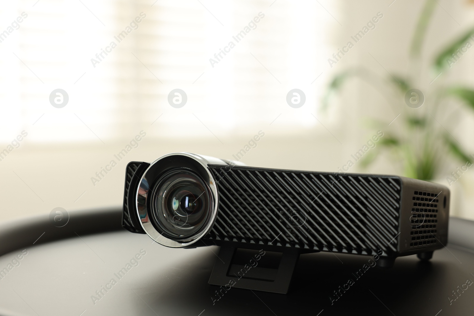 Modern video projector on black table indoors, closeup Photo of Modern video projector on black table indoors, closeup