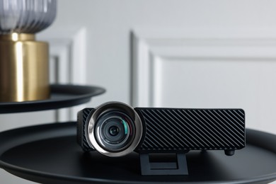 Photo of Modern video projector on black table indoors