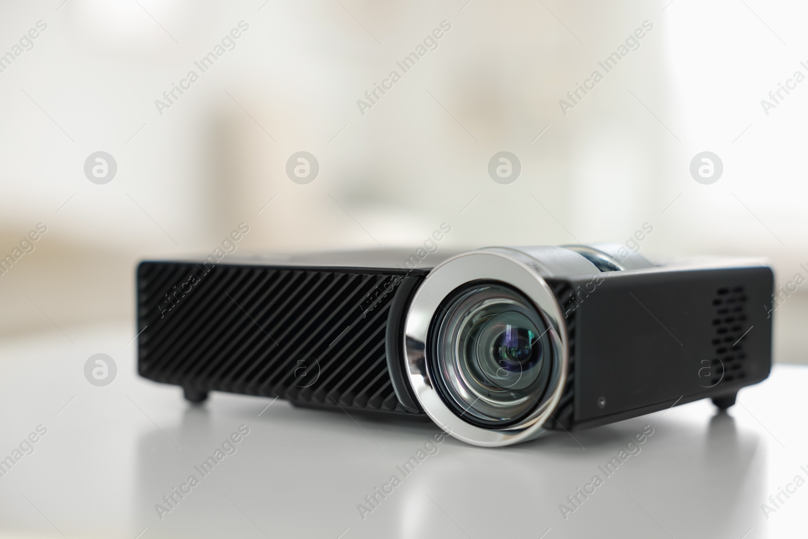 Modern video projector on white table indoors, closeup Photo of Modern video projector on white table indoors, closeup