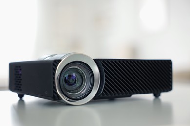 Photo of Modern video projector on white table indoors, closeup