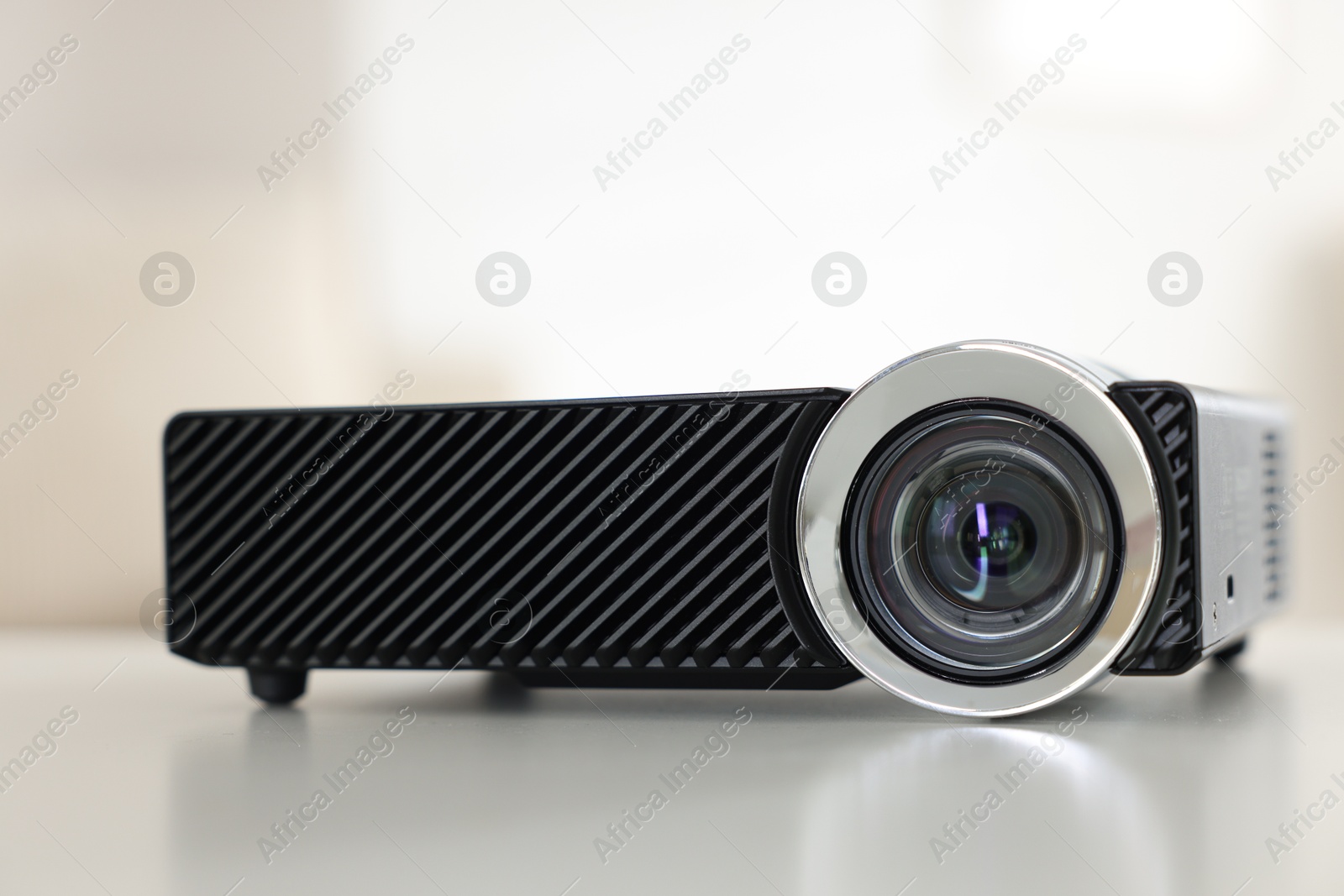 Modern video projector on white table indoors, closeup Photo of Modern video projector on white table indoors, closeup