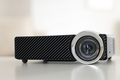 Photo of Modern video projector on white table indoors, closeup
