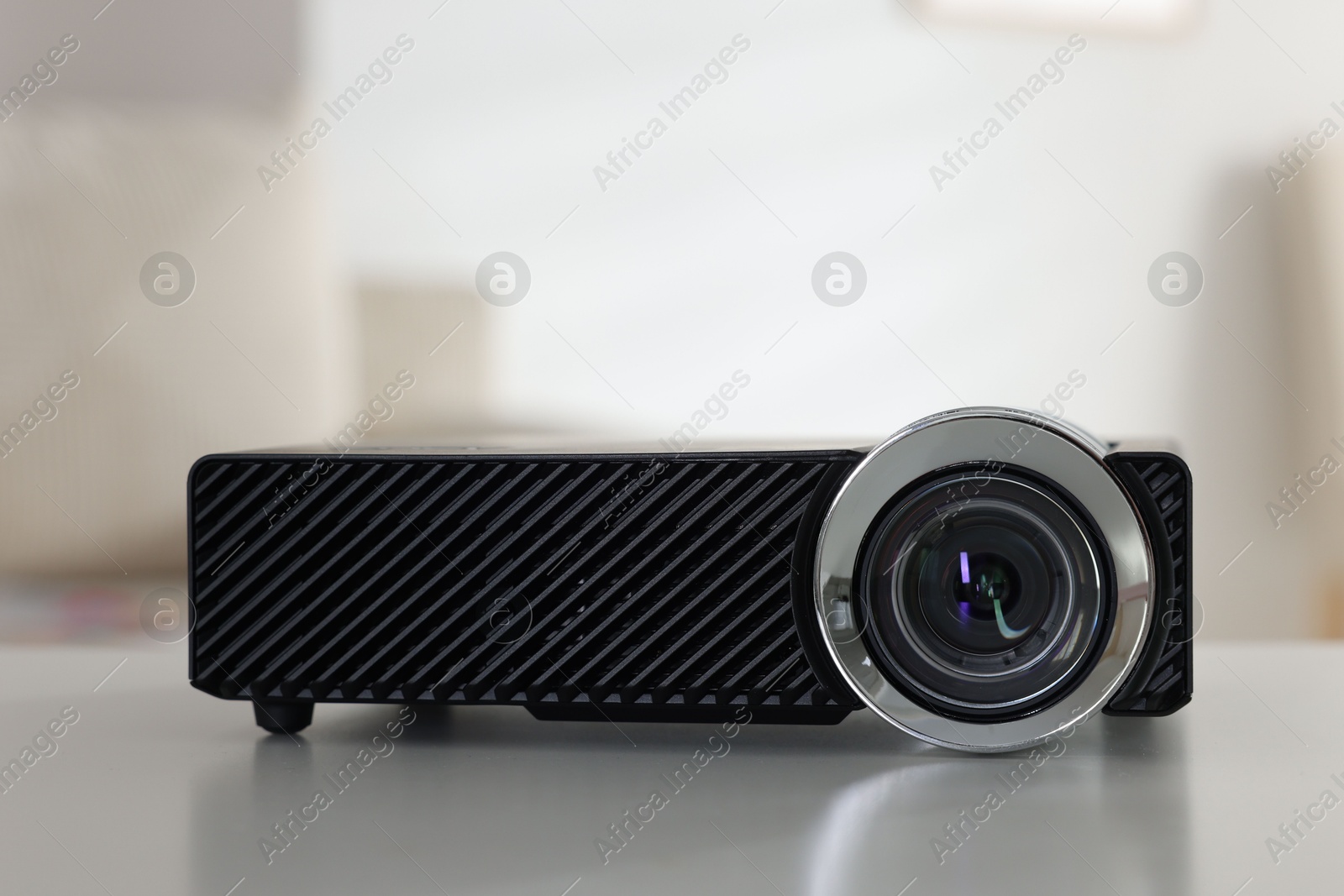 Modern video projector on white table indoors, closeup Photo of Modern video projector on white table indoors, closeup