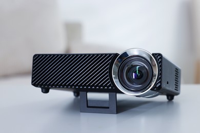 Photo of Modern video projector on white table indoors, closeup